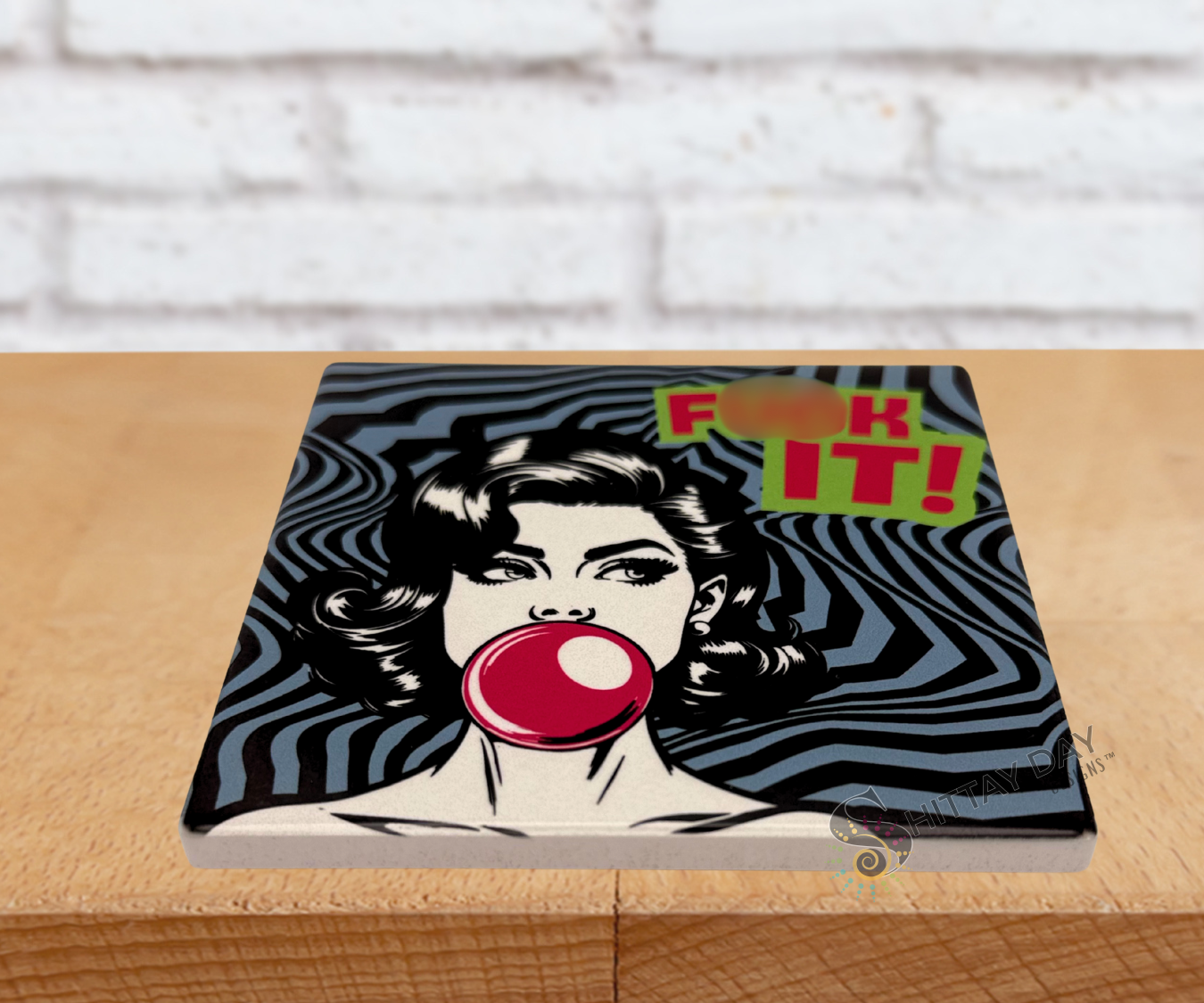 Pop art-style ceramic coaster with a woman blowing a bubble gum bubble and  a bold exclamation reading 'F*ck It!' text on an abstract grey and black background.