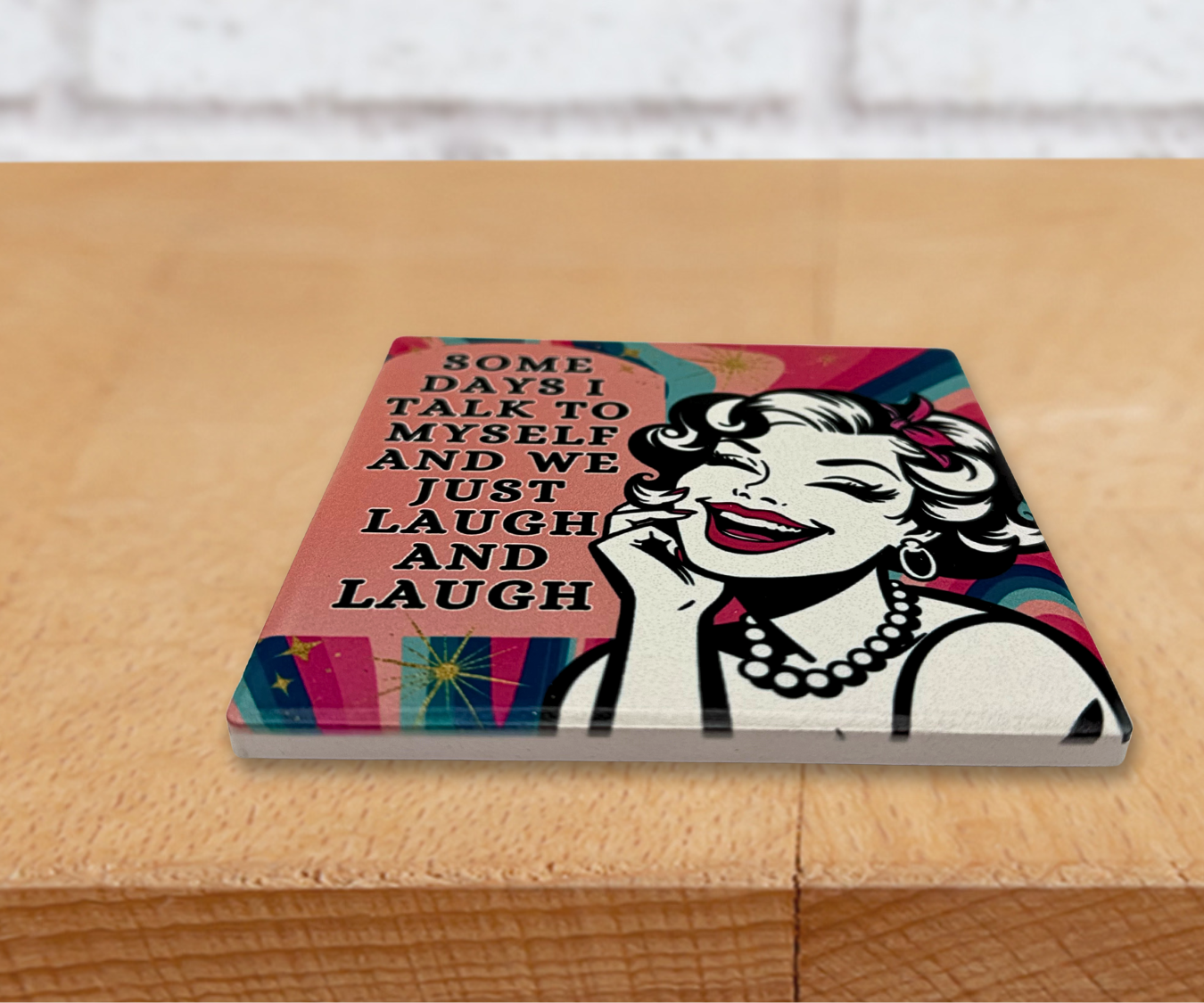 Decorative multicolor ceramic coaster with a stylized illustration of a woman smiling and the funny quote 'SomeDays I Talk To Myself And we Just Laugh And Laugh' on a colorful background.