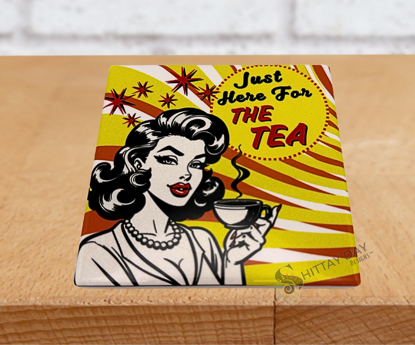 Pop culture style ceramic coaster with a retro-style illustration of a woman holding a tea cup and the sassy text 'Just Here For The Tea' on a vivid yellow, orange, and white background.