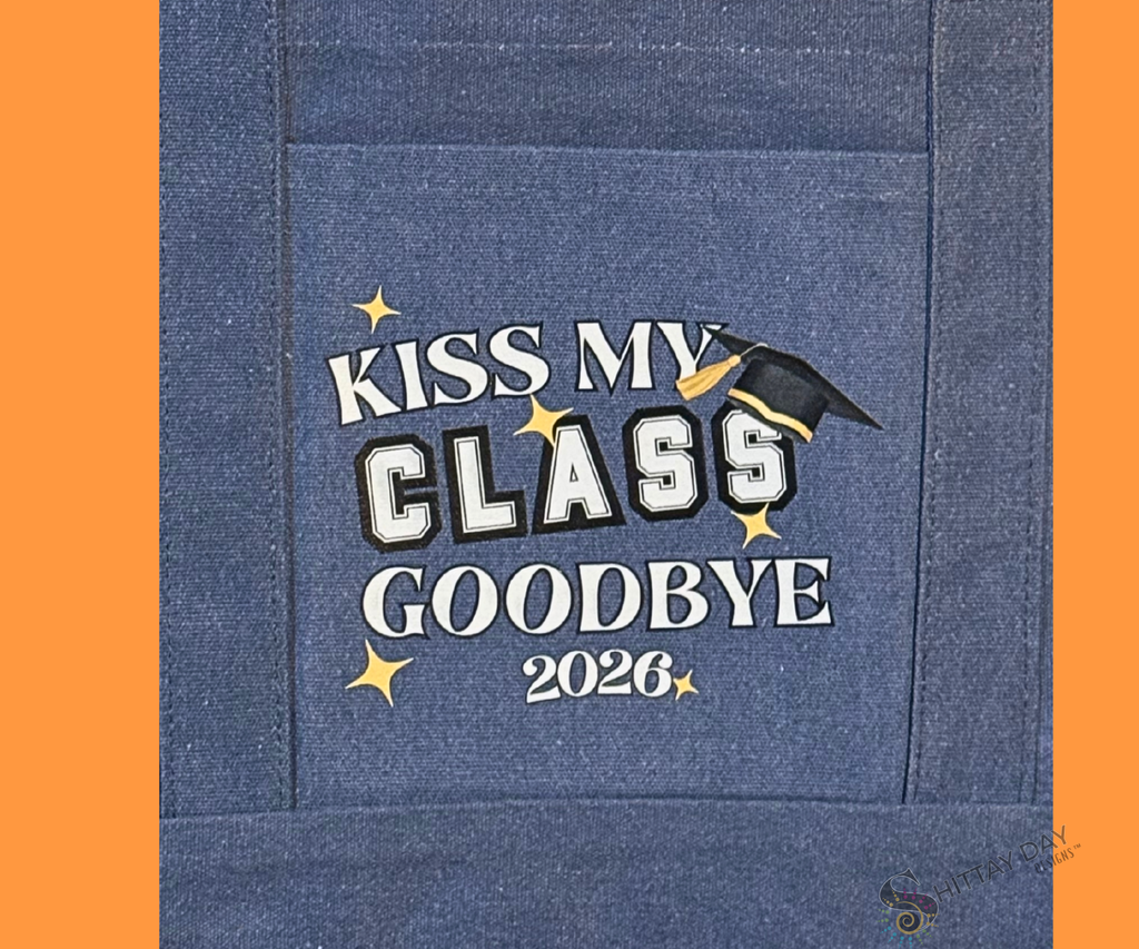 Blue denim pocket tote close up of graduation design with 'Kiss My Class Goodbye 2026' text and graduation cap design merchandised on an orange background.