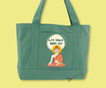 Green pocket tote bag with "let that shit go" text in a circle design featuring the image of a buddha-dharma holding a white lotus flower image.  Merchandised on a light green background.