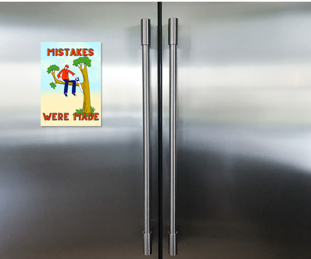 Fridge with a humorous aluminum Cardsign keepsake greeting card with cartoon depictions on character on a tree branch sawing it and text  'Mistakes Were Made'.