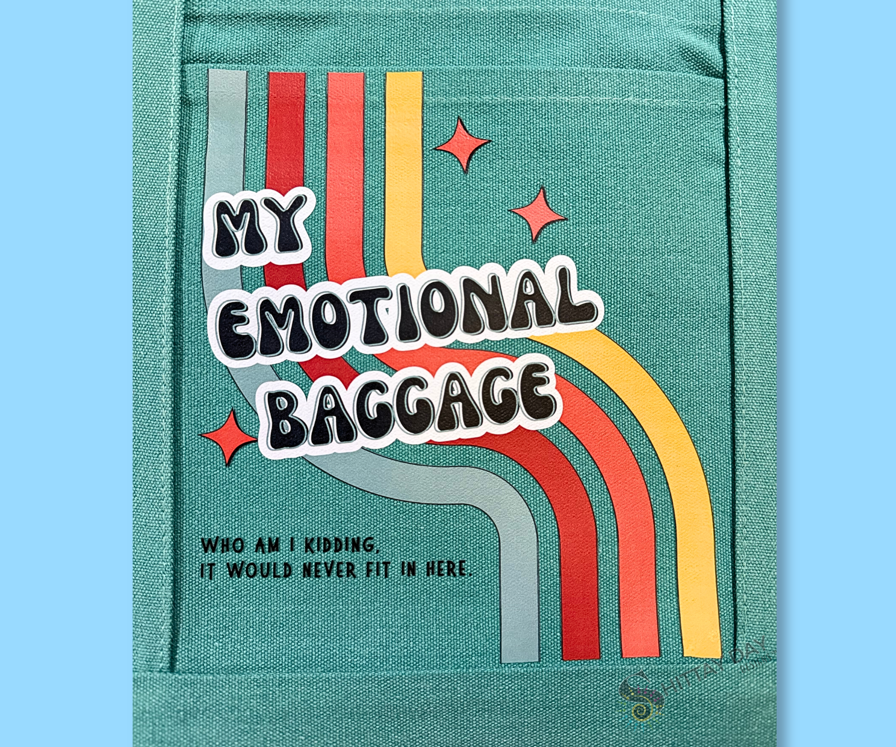 Teal pocket tote close up of design with 'My Emotional Baggage, who am I kidding, it would never fit' text  a multicolor retro stripes, and three orange starbursts. Merchandised on an light blue background.
