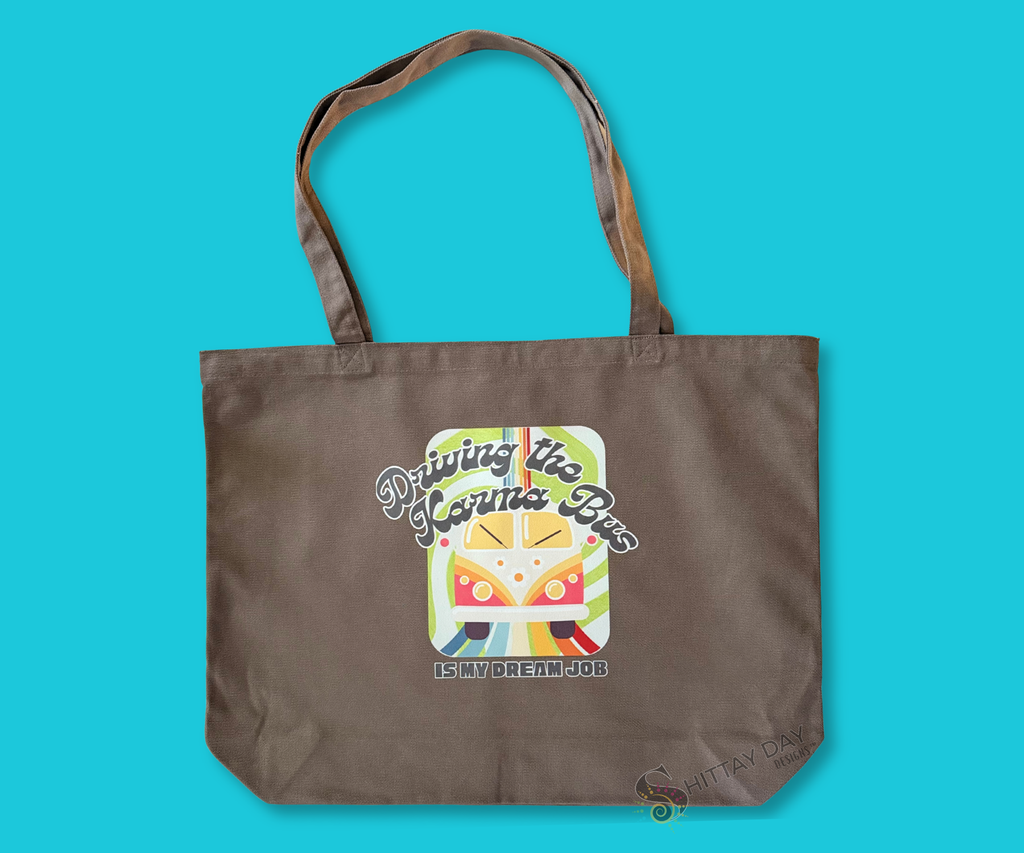 Decorative gray brown tote bag with a colorful graphic of a retro bus, colorful swirl pattern design, and text merchandised on a blue background