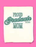 Natural color folded tshirt with a close up of the design; 'Proud Graduate Mom 2026'  teal text. Merchandised on a pink background.