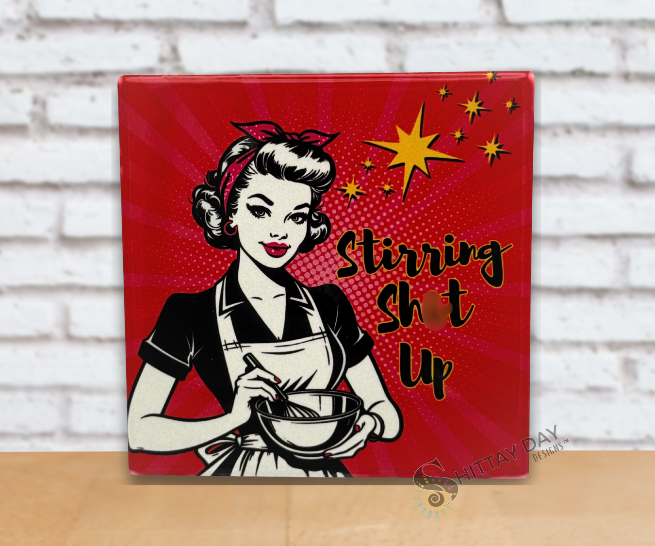Pop Culture retro vibe ceramic coaster with  a woman in an apron holding a  whisk and bowl with the sassy text 'Stirring Sh*t Up' on a red starburst background.